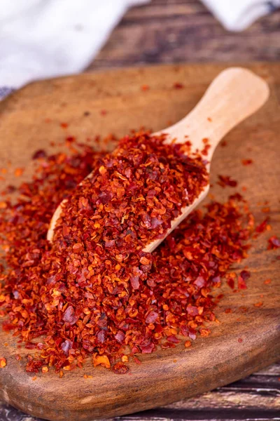 Dried red pepper flakes. Spice chili pepper flakes in wooden spoon on wood background