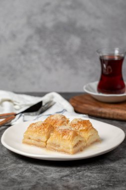 Sütlü ve fındıklı baklava. Türk mutfağı lezzetleri. Siyah arka planda süt olan baklava. Yerel adı Sutlu Nuriye. 