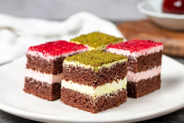 Small cake slices. Pistachio and raspberry cake slices. Set of different tartlets or cakes. Bakery products. Close up