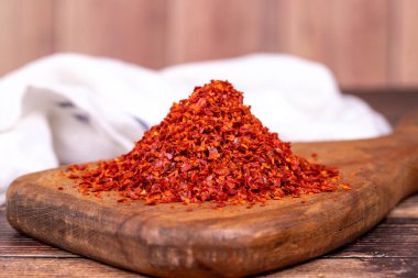 Kurutulmuş kırmızı biber taneleri. Baharatlar ve bitkiler. Ahşap arka planda bibersiz tanecikler. Kapat.