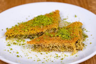 Fıstıklı kadayif. Türk usulü şerbet tatlısı. Ahşap arka planda fıstıklı Kadayif tatlısı. Kapat.