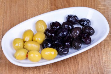 Doldurulmuş yeşil zeytin ve siyah zeytin. Doğal olarak seramik bir kasede zeytin. Kapat.