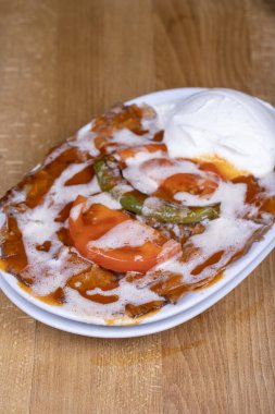 İskender Kebap. İskender kebabı, tereyağı ve yoğurt ile ahşap bir zeminde. Türk mutfağı lezzetleri. Yemek turizmi. Kapat.