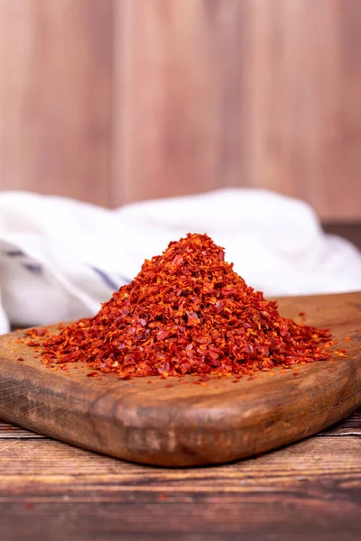 Dried red pepper flakes. Spices and herbs. Chilli pepper seedless flakes on wood background. Close up