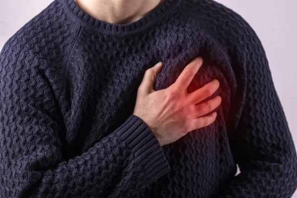 Man having a heart attack. Man holding his chest in acute pain. Heart attack symptom-Health and medical concept. Painful area highlighted in red