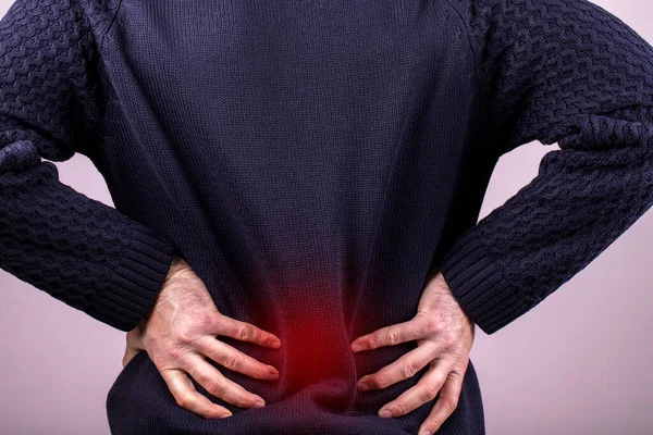 Backache man. Intervertebral hernia, lumbar pain, kidney inflammation, man suffering from backache at home, spinal disc disease, health problems concept. painful area highlighted in red
