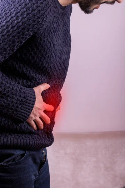 有严重胃痛的人坐在家里 手部成熟的男人握住腹部有疼痛 腹泻或消化不良的问题 红色醒目的痛苦区域 — 图库照片