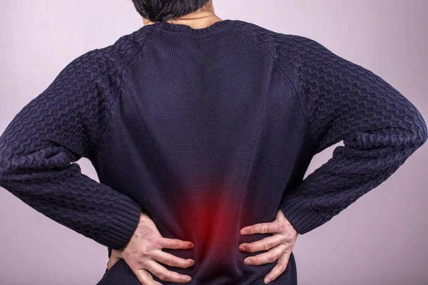 Backache man. Intervertebral hernia, lumbar pain, kidney inflammation, man suffering from backache at home, spinal disc disease, health problems concept. painful area highlighted in red