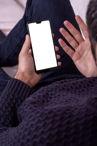 Cell phone blank white screen mockup. Man on sofa looking at phone in white screen mockup