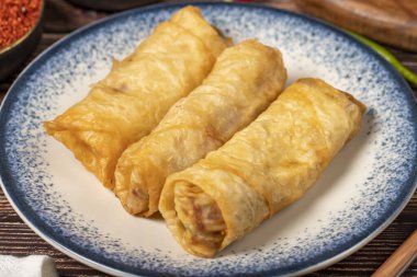 Ahşap arka planda Pacanga pastası. Pastırmalı fillo hamur işi. Türk mutfağı lezzetleri. Yerel adı Pacanga Boregi. Kapat.