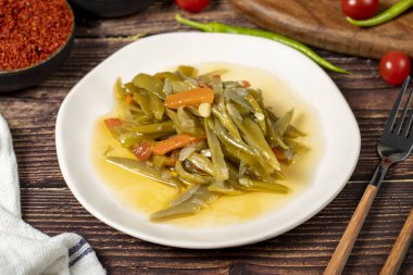 Ahşap zemin üzerinde zeytin yağı olan yeşil fasulye yemeği..