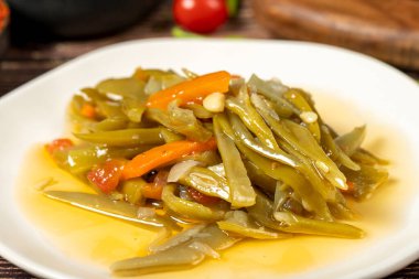 Ahşap zemin üzerinde zeytin yağı olan yeşil fasulye yemeği. Kapat.