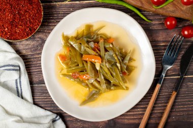 Ahşap zemin üzerinde zeytin yağı olan yeşil fasulye yemeği. Üst görünüm