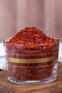 Kırmızı biber taneleri. Ezilmiş kırmızı biber ya da ahşap arka planda cam kasede kurutulmuş kırmızı biber. Kapat.