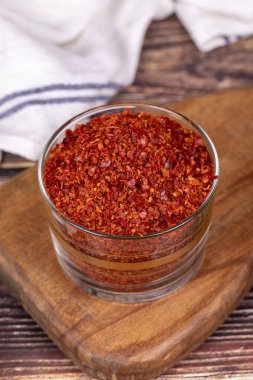 Kırmızı biber taneleri. Ezilmiş kırmızı biber ya da ahşap arka planda cam kasede kurutulmuş kırmızı biber.