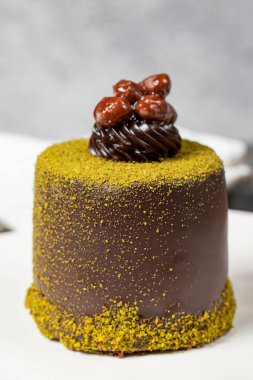 Çikolatalı pasta. Fıstıklı pasta ve koyu arkaplanda çikolata kreması. Pastane tatlıları. Kapat.