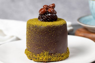 Çikolatalı pasta. Fıstıklı pasta ve koyu arkaplanda çikolata kreması. Pastane tatlıları. Kapat.