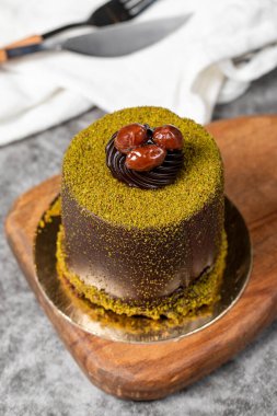 Çikolatalı pasta. Fıstıklı pasta ve koyu arkaplanda çikolata kreması. Pastane tatlıları. Kapat.