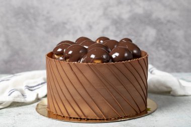 Çikolata kaplı profiterol doğum günü pastası. Gri arka planda çikolatalı pasta.