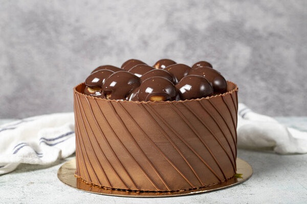 Шоколад покрыл профитроли праздничный торт. Шоколадный торт на сером фоне