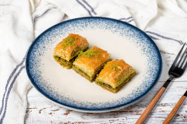 Ahşap arka planda fıstıklı baklava. Antep fıstıklı geleneksel Türk baklavası. Şerbet tatlısı