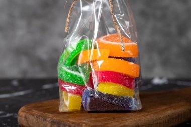 Jelibon şekerlemeleri koyu bir arka planda paketlenmiş meyve dilimleri şeklinde. Kapat.