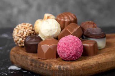 Çikolatalı Praline. Tahta servis tahtasının üzerinde çeşit çeşit trüf ya da pralin çikolataları. Kapat.