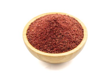 Sumac beyaz arka planda izole edildi. Kurumuş toprak, kırmızı Sumac tozu, ahşap kasede baharatlar.