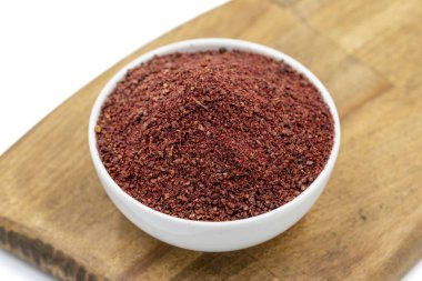Sumac beyaz arka planda izole edildi. Kurumuş toprak, kırmızı Sumac tozu, ahşap kasede baharatlar.