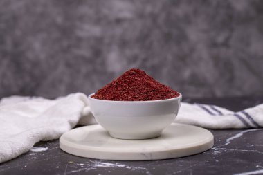 Karanlık arka planda Sumac. Kurumuş toprak, kırmızı Sumac tozu, ahşap kasede baharatlar.