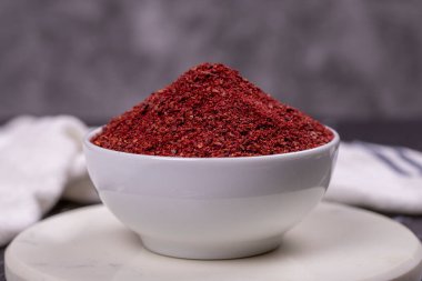 Karanlık arka planda Sumac. Ahşap kasede kurutulmuş kırmızı Sumac tozu baharatları. Kapat.