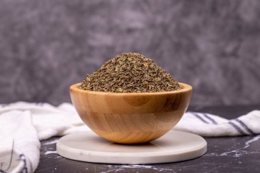 Arka planda kurutulmuş fesleğen. Ahşap kasede kurutulmuş fesleğen tozu baharatları. Baharat konsepti