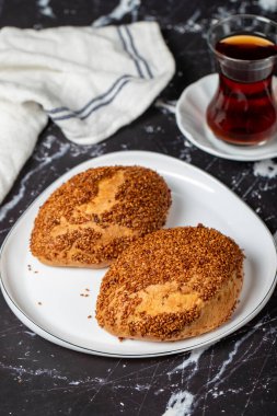 Karanlık arka planda susamlı ve peynirli börek. Türk sokak yemeği. Peynirli pogaca. Kapat.