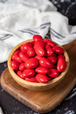 Çikolatalı badem sürahi. Koyu arka planda tahta kasede kırmızı çikolata süprüntüsü. Kapat.