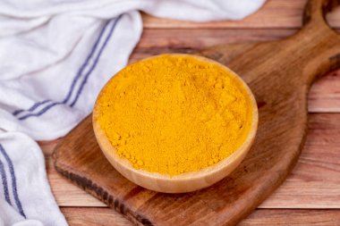 Ahşap arka planda zerdeçal tozu. Tahta kasede kurumuş zerdeçal tozu baharatları.