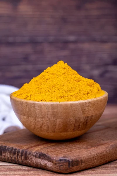 stock image Powdered turmeric on wooden background. Dried ground turmeric powder spices in wooden bowl. Close up