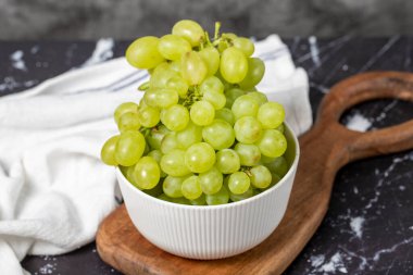 Kasede yeşil üzüm. Organik tarım ürünleri. Koyu arkaplanda lezzetli yeşil üzüm demetleri. Kapat.