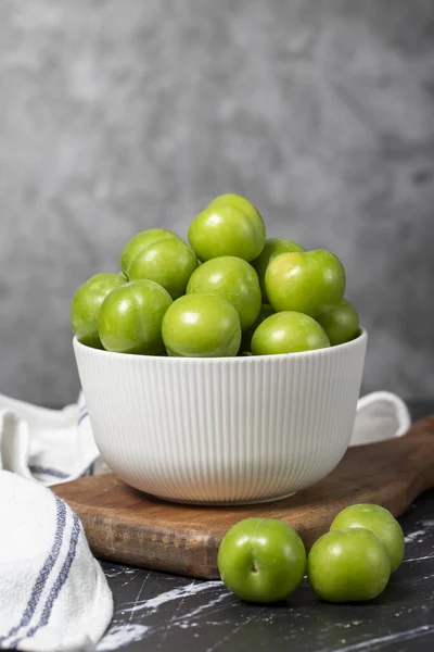 stock image Green plum in bowl. Organic farm products. Sweet or sour plum on a dark background