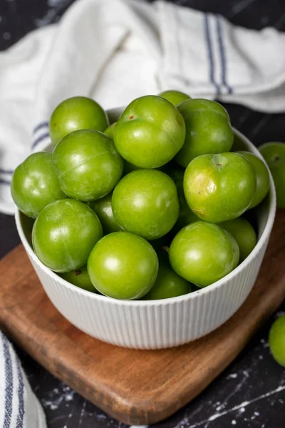 stock image Green plum in bowl. Organic farm products. Sweet or sour plum on a dark background. Close up