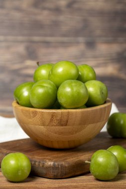 Kasede yeşil erik. Organik tarım ürünleri. Ahşap zemin üzerinde taze erik. Kapat.
