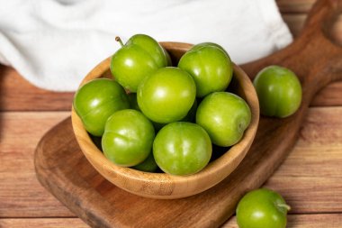 Kasede yeşil erik. Organik tarım ürünleri. Ahşap zemin üzerinde taze erik. Kapat.