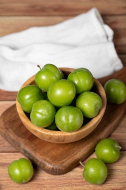 Kasede yeşil erik. Organik tarım ürünleri. Ahşap zemin üzerinde taze erik