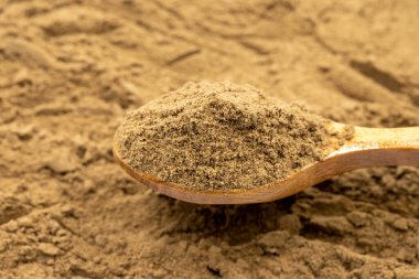 Arka plan olarak tüm baharat tozu, baharat ya da baharat yığını. Tahta kaşıkta baharat tozu. Pimento baharat, Jamaika biberi ve talaş.