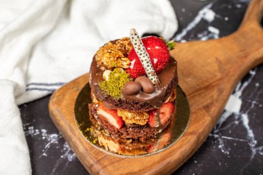 Çikolata, Çilek ve Fıstıklı Kek. Koyu arkaplanda lezzetli bir pasta.