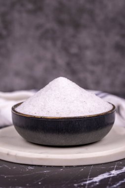 Koyu arkaplanda iyot olmayan tuz. Doğal minare iyonik olmayan öğütücü tuz kasesinde. Baharat konsepti. Kapat.