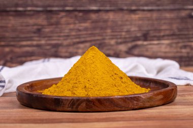 Ahşap arka planda köri tozu. Tahta kasede köri tozu. Baharat ve kurutulmuş otların karışımı. Baharat konsepti