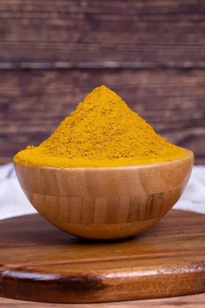 Curry powder on wooden background. Curry powder in wooden bowl. Mixture of spices and dried herbs. Spice concept. Close up