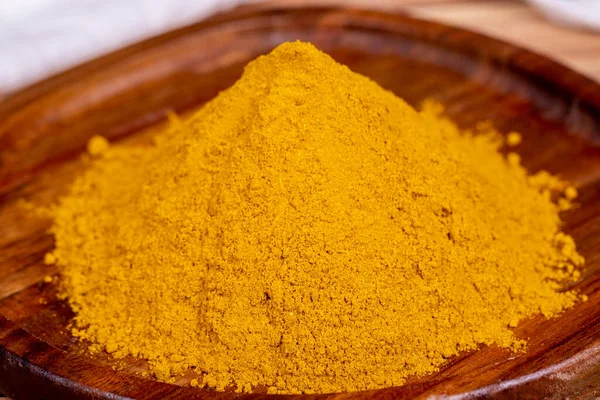 Curry powder on wooden background. Curry powder in wooden bowl. Mixture of spices and dried herbs. Spice concept. Close up
