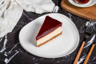 Koyu arkaplanda ahududu aromalı cheesecake. beyaz tabakta bir parça cheesecake