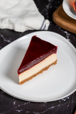 Koyu arkaplanda ahududu aromalı cheesecake. beyaz tabakta bir parça cheesecake